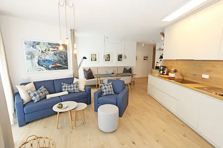 gemütlicher Wohn-/ Essbereich mit hellen Eichenholz Möbeln, Sessel, Couch mit Leselampe, Beistelltische, Stehlampe & 65“ Smart-TV 