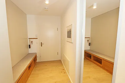 Eingangsbereich mit einer breiten Sitzbank inklusive Schubfächern, Ganzkörperspiegel, Garderobe und einem geräumigen Schrank für Strandutensilien und Koffer