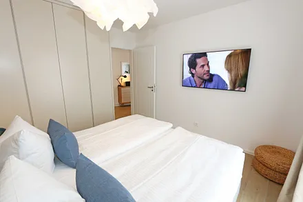 Schlafzimmer mit komfortablem Boxspringbett (1,80 m x 2,00 m), durchgehendem Topper, Nachttischablagen und großem Kleiderschrank sowie Smart-TV
