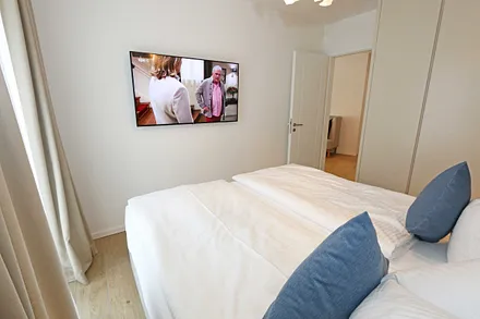 Schlafzimmer mit komfortablem Boxspringbett (1,80 m x 2,00 m), durchgehendem Topper, Nachttischablagen und großem Kleiderschrank sowie Smart-TV
