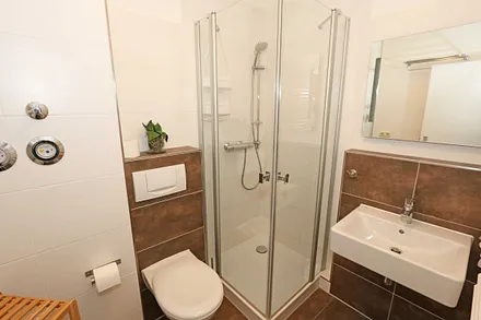 Badezimmer mit ebenerdiger Dusche, Waschplatz, WC, Handtuchheizkörper, Kosmetikspiegel und Fön