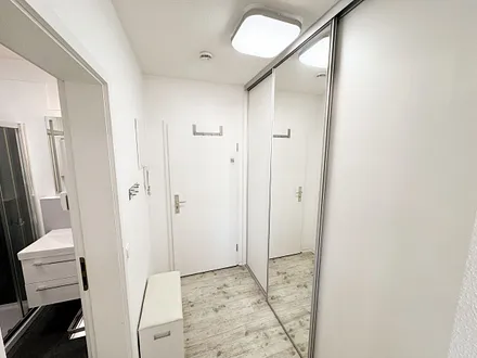 freundlicher Eingangsbereich mit großem Spiegel und Schuhablage mit Sitzbank