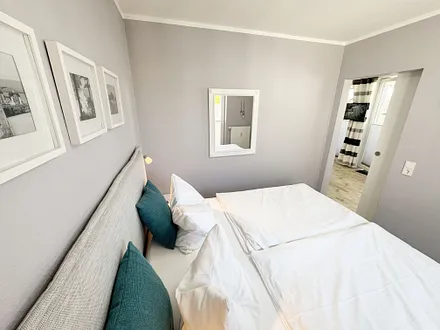Schlafzimmer mit Boxspringbett, komfortabler Topper, Nachttischablagen sowie Verdunkelungsvorhang