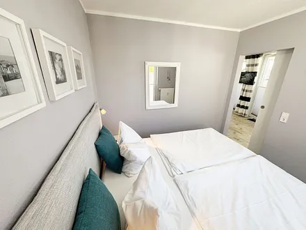 Schlafzimmer mit Boxspringbett, komfortabler Topper, Nachttischablagen sowie Verdunkelungsvorhang