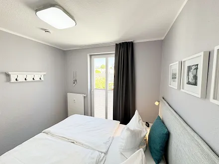 Schlafzimmer mit Boxspringbett, Nachttischablagen sowie Verdunkelungsvorhang
