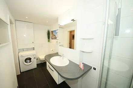 Badezimmer mit Waschmaschine, Waschbecken und WC