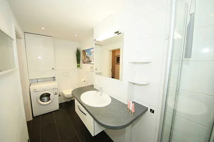 Badezimmer mit Waschmaschine, Waschbecken und WC