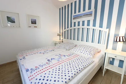 Schlafzimmer mit einem Doppelbett (1,80 m x 2,00 m), Qualitäts- Latexmatratzen, verstellbarem Lattenrost, Kleiderschrank und Verdunklungsplissees 