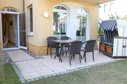 überdachte und bestuhlte Terrasse (Nordost) mit Strandkorb und Blick auf den Kurpark - vom Wohnbereich begehbar