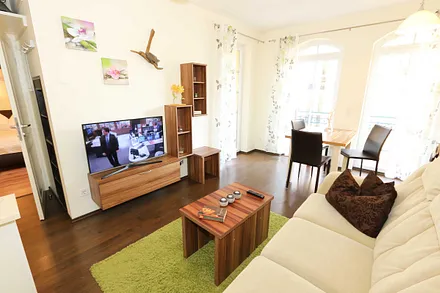 Wohnzimmer (20 m²) mit einer Sitzcouch, Tisch, Smart-TV und Blu-Ray-Player