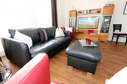 gemütliche Sitzecke bestehend aus Ledercouch (ausklappbar 1,40 m x 2,00 m mit Lattenrost und Matratze) und zwei Sesseln, Leselampe, Smart-TV.