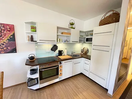 moderne Küchenzeile mit Kühlschrank, separates Gefrierfach, Ceranfeld, Backofen, Mikrowelle, Geschirrspüler und diversen Küchenutensilien 