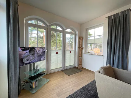 Wohnzimmer mit gemütlicher Sitzecke, Leselampe, Smart-TV, DVD-Player und Telefon