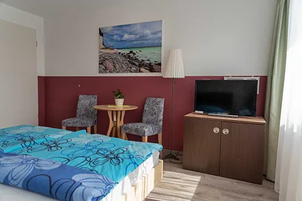 Wohn/Schlafbereich mit 43 Zoll Smart TV, hochwertigen Teppich, Doppelbett mit Einzelmatratzen (1,80 m x 2,00 m), geräumiger Kleiderschrank mit Safe, Sideboard mit Mini-Stereoanlage mit CD-Player