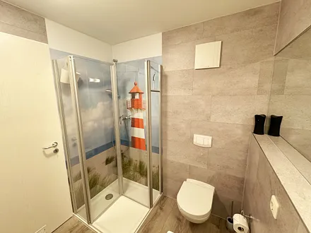 innenliegendes Badezimmer mit WC, Dusche, Waschtisch mit Unterschrank, Fön, Kosmetikspiegel, großem Wandspiegel, Handtuchheizkörper und einem Ablageregal