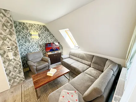 offener Wohnbereich mit Eckcouch, ein Sessel, Stehlampe, Sessel, Couchtisch, 48 Zoll Smart-TV, Hifi Microanlage mit CD-Player, MP3, UKW-Funktion, USB und Bluetooth mit NFC und ein DAB-Radio