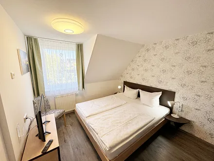 Schlafzimmer mit Doppelbett ( 2 x 0,90 m x 2,00 m ), Nachttischablagen mit Leselampen, 17 Zoll LED-TV, Kleiderschrank mit Safe, Sideboard, Verdunklungsgardinen sowie Insektenschutzgitter