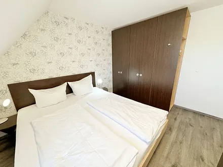 Schlafzimmer mit Doppelbett ( 2 x 0,90 m x 2,00 m ), Nachttischablagen mit Leselampen, 17 Zoll LED-TV, Kleiderschrank mit Safe, Sideboard, Verdunklungsgardinen sowie Insektenschutzgitter
