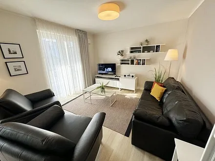Wohnbereich mit modernen weißen Hülsta Möbeln, ein gemütliches Ledersofa, zwei Sessel, zwei Couchtischen, Stehlampen, DAB Radio mit CD-Player und Bluetooth, Smart-TV mit Soundbar & Blu-Ray Player
