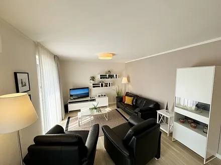 Wohnbereich mit modernen weißen Hülsta Möbeln, ein gemütliches Ledersofa, zwei Sessel, zwei Couchtischen, Stehlampen, DAB Radio mit CD-Player und Bluetooth, Smart-TV mit Soundbar & Blu-Ray Player