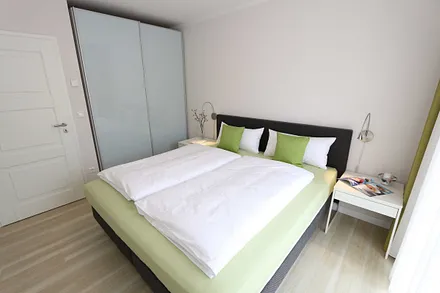 Schlafzimmer mit großem Schwebetürenschrank, bequemen Boxspringbett von Hülsta (1,80 m x 2,00 m, durchgehender Topper), Nachttischablagen und Leselampen