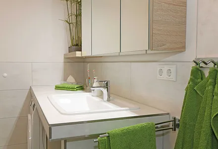 modernes Badezimmer mit ebenerdiger komfortabler Regendusche, Waschplatz, WC, Kosmetikspiegel, Fön, Spiegelschrank und einen Handtuchtrockner
