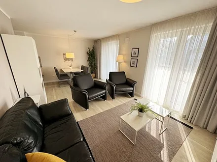 Wohnbereich mit modernen weißen Hülsta Möbeln, ein gemütliches Ledersofa, zwei Sessel, zwei Couchtischen, Stehlampen, DAB Radio mit CD-Player und Bluetooth, Smart-TV mit Soundbar & Blu-Ray Player