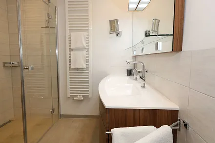 Badezimmer mit Regendusche, großzügigem Doppelwaschtisch, großem Spiegel, Kosmetikspiegel, Handtuchtrockner und Fön