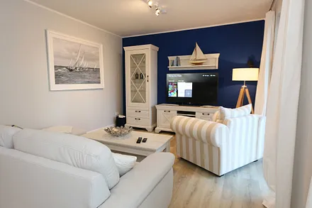 Wohnbereich mit großzügiger Sitzgruppe (ausziehbare Liegefläche von 1,23 m x 1,98 m), gemütlichem Lounge Sessel, Leselampe, Lowboard mit Smart-TV (55") & Blu-Ray-Player