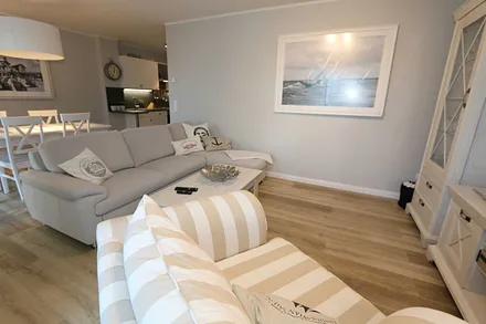 Wohnbereich mit großzügiger Sitzgruppe (ausziehbare Liegefläche von 1,23 m x 1,98 m), gemütlichem Lounge Sessel, Leselampe, Lowboard mit Smart-TV (55") & Blu-Ray-Player