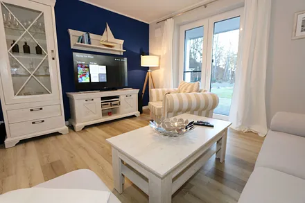 Wohnbereich mit großzügiger Sitzgruppe (ausziehbare Liegefläche von 1,23 m x 1,98 m), gemütlichem Lounge Sessel, Leselampe, Lowboard mit Smart-TV (55") & Blu-Ray-Player