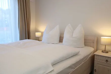 Schlafzimmer  im Landhausstil mit großem Doppelbett (1,60 m x 2,00 m), 5-Zonen-Federkern-Matratzen, verstellbare Lattenroste, Nackenkissen, Nachttischablagen und geräumigen Einbauschrank