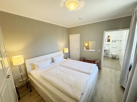 Schlafzimmer mit Doppelbett und Blick ins Badezimmer