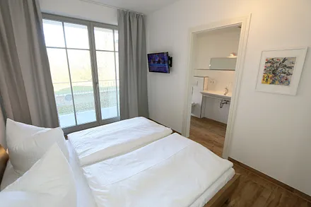 Schlafzimmer (en-suite) mit bequemen Komfort- Doppelbett (1,80 m x 2,00 m), hochwertigen Matratzen, verstellbaren Lattenrosten, Kleiderschrank, Nachttische und Wecker