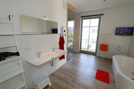 großes Wellness-Bad mit Sauna, freistehender Badewanne, bodengleicher Dusche, WC, Waschtisch, Kosmetikspiegel, elektrisch beheizbarem Handtuchhalter, Flachbild-TV und Fön 