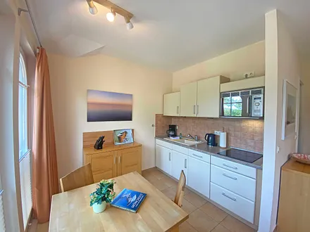 angrenzende Küchenzeile mit Keramikspüle, 3-Zonen-Glaskeramik-Kochfeld, Kühlschrank mit Gefrierfach, Geschirrspüler, Mikrowellen-Dunstabzugs-Kombination, Kaffeemaschine, Wasserkocher und Toaster