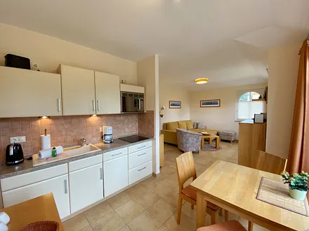 angrenzende Küchenzeile mit Keramikspüle, 3-Zonen-Glaskeramik-Kochfeld, Kühlschrank mit Gefrierfach, Geschirrspüler, Mikrowellen-Dunstabzugs-Kombination, Kaffeemaschine, Wasserkocher und Toaster