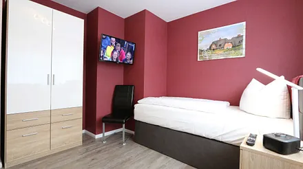 Schlafzimmer mit Einzelboxspringbett (100 x 200 cm) und einer Schlafcouch (140 x 195 cm),Nachtschränke,dimmbaren Nachttischlampen,Radiowecker,2- türiger Kleiderschrank,32 Zoll Flachbild mit Smart-TV