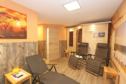 Untergeschoss mit Sauna, separate Walk-In-Dusche, Waschbecken und WC, angrenzendem Ruheraum mit Liegen und Relaxstühlen zur freien Verfügung sowie ein elektrischer Wandkamin