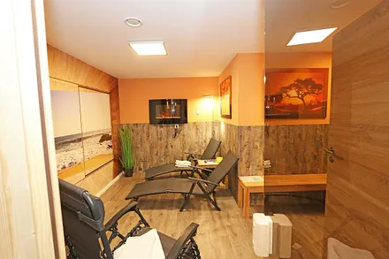 Untergeschoss mit Sauna, separate Walk-In-Dusche, Waschbecken und WC, angrenzendem Ruheraum mit Liegen und Relaxstühlen zur freien Verfügung sowie ein elektrischer Wandkamin