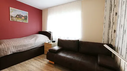 Schlafzimmer mit Einzelboxspringbett (100 x 200 cm) und einer Schlafcouch (140 x 195 cm),Nachtschränke,dimmbaren Nachttischlampen,Radiowecker,2- türiger Kleiderschrank,32 Zoll Flachbild mit Smart-TV