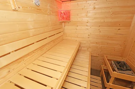 Untergeschoss mit Sauna, separate Walk-In-Dusche, Waschbecken und WC, angrenzender Ruheraum mit Liegen und Relaxstühlen zur allgemeinen freien Nutzung sowie ein elektrischer Wandkamin