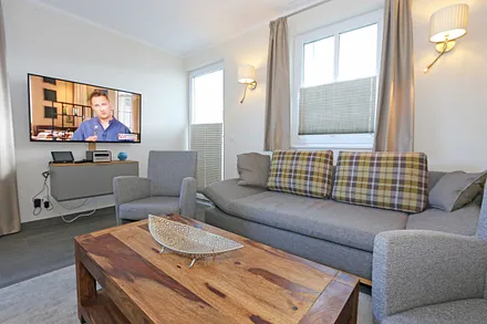 offener Wohnbereich mit gemütlicher Couch, Couchtisch, 2 Leselampen (integriert in den Wandleuchten bei der Couch), Smart-TV, Blu-Ray Player sowie eine Mini-Stereo-Anlage von Sonoro 