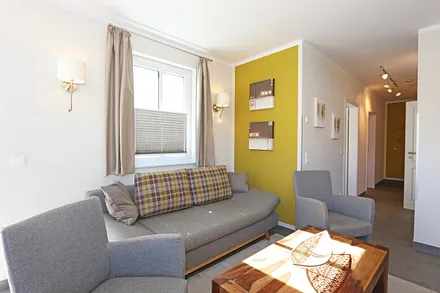 offener Wohnbereich mit gemütlicher Couch, Couchtisch, 2 Leselampen (integriert in den Wandleuchten bei der Couch), Smart-TV, Blu-Ray Player sowie eine Mini-Stereo-Anlage von Sonoro 