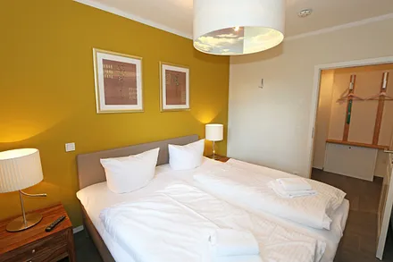 Schlafzimmer mit einem Boxspringbett (1,80 m x 2,00 m), Smart-TV, Nachttischschränken und einen Kleiderschrank