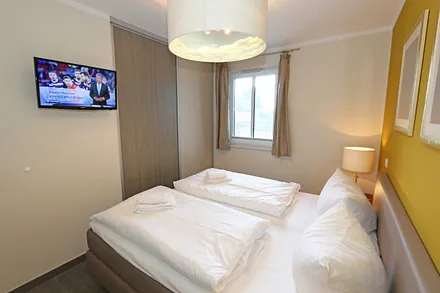 Schlafzimmer mit einem Boxspringbett (1,80 m x 2,00 m), Smart-TV, Nachttischschränken und einen Kleiderschrank