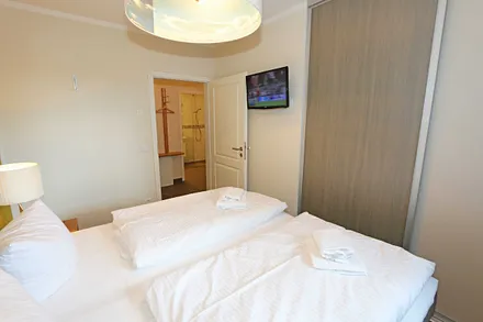 Schlafzimmer mit zwei einzelnen Boxspringbetten (0,90 m x 2,00 m, die Betten sind hier mit Rollen versehen und zusammenschiebbar), Nachttischschränken, Flachbild-TV und einen Kleiderschrank