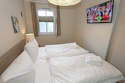 Schlafzimmer mit zwei einzelnen Boxspringbetten (0,90 m x 2,00 m, die Betten sind hier mit Rollen versehen und zusammenschiebbar), Nachttischschränken, Flachbild-TV und einen Kleiderschrank