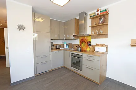 Küchenzeile mit Induktionsfeld, Backofen, Geschirrspüler, Kühlschrank mit Gefrierfach, Kaffeemaschine, Wasserkocher, Toaster und diversen Küchenutensilien