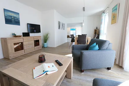 offener Wohnbereich mit gemütlicher Sitzecke, Couchtisch, Sessel, Leselampe, Smart-TV mit CD-Player, DAB Radio und Blu-Ray-Player